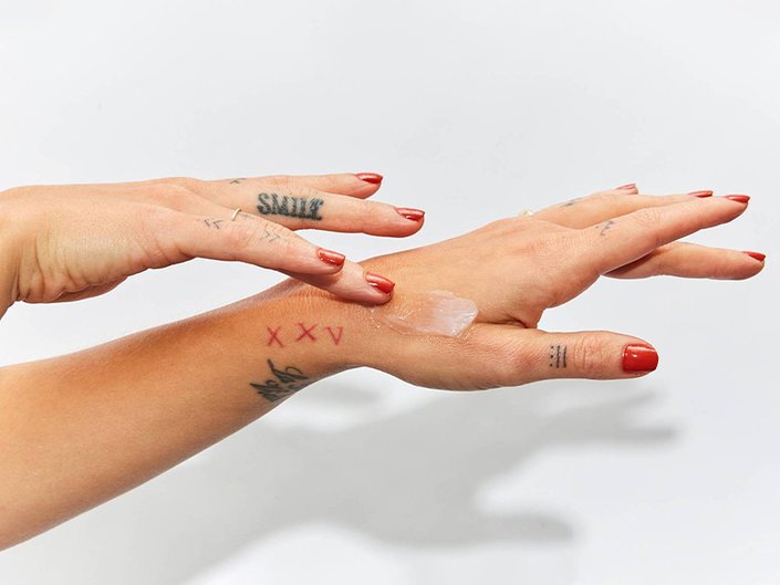 Picture of a model with tattooed hands applying lotion