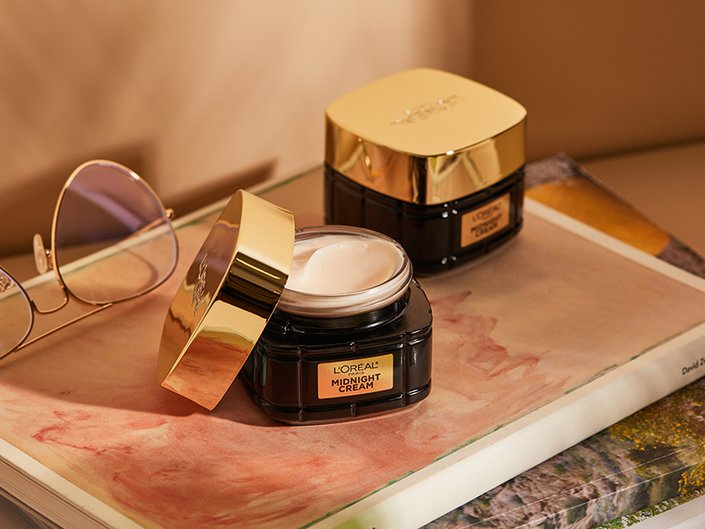 Picture of two of the L’Oréal Paris Age Perfect Cell Renewal Midnight Creams on a wooden tray cast in golden light