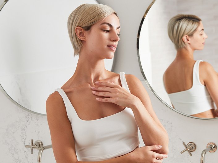 person posing in a mirror touching their decellotage