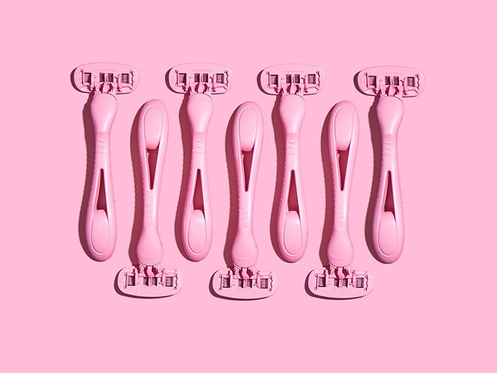 A flatlay of multiple pink razors on a matching pink background 