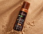 An image of the L'Oréal Paris Skincare Sublime Bronze Self-Tanning Water Mousse on top of sand