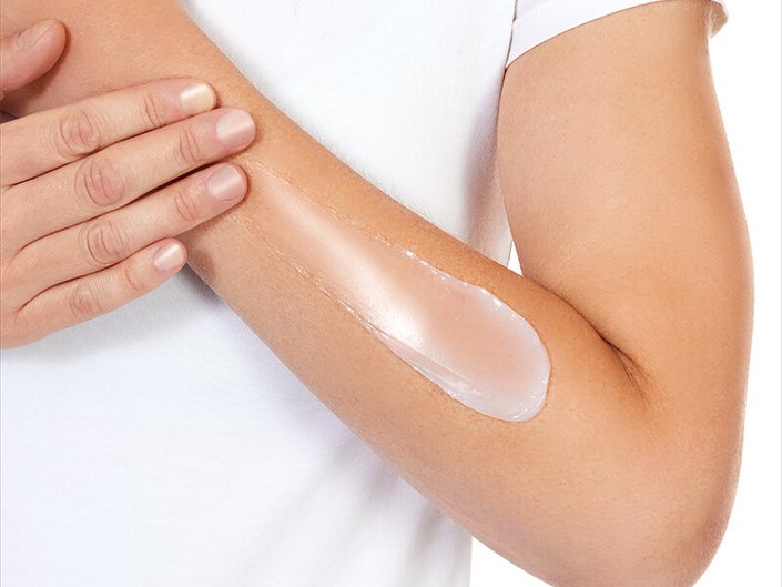 Close-up of a hand applying a soothing salve to cracked skin, illustrating the use of different skin treatment products.