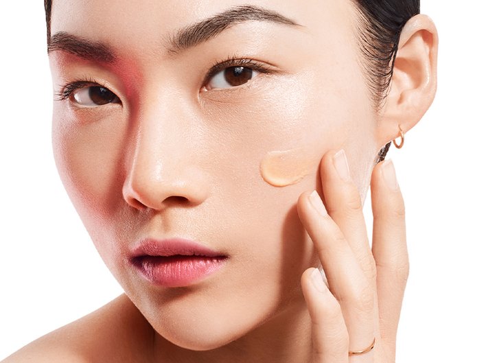 Photo of a woman and applying moisturizer to her cheek