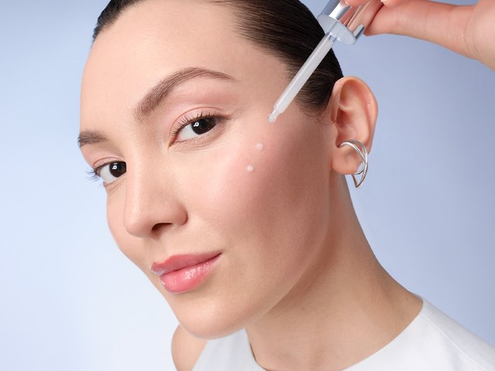 Image of woman applying serum to face