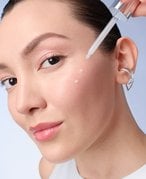 Image of woman applying serum to face