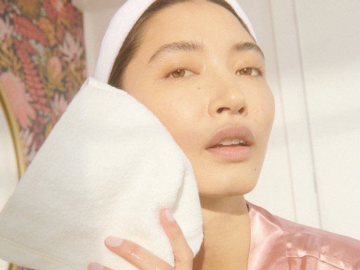 person washing face with a washcloth