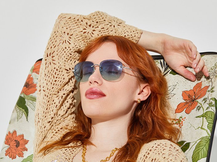 Picture of a red-haired model reclining and wearing sunglasses