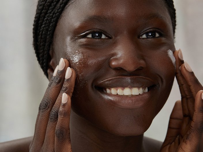 Picture of a model smiling and exfoliating their face