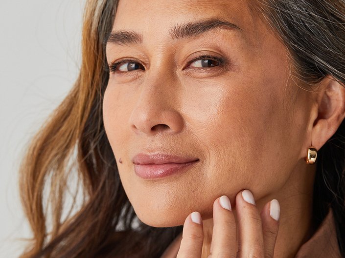 Picture of a mature model softly smiling and touching their chin
